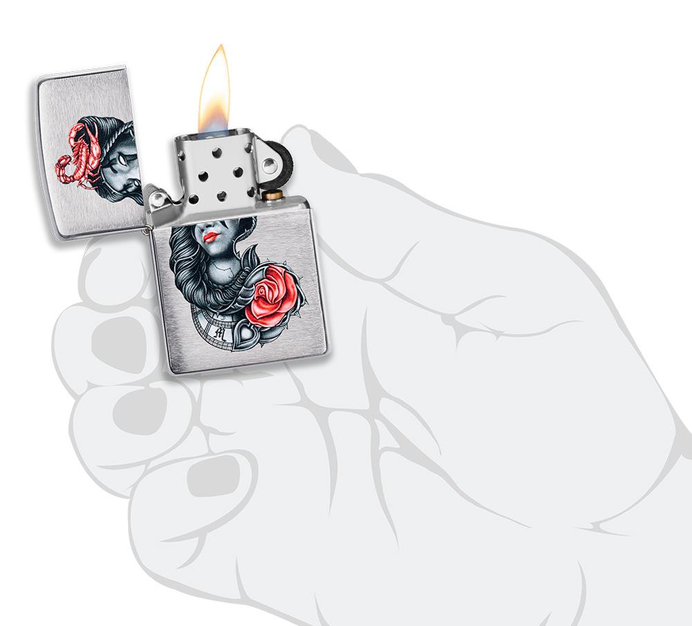 stylised Tattoo Design Brushed Chrome Windproof Lighter lit in hand