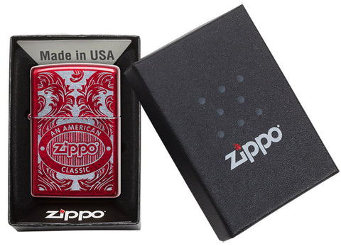 Briquet Zippo rouge vue de face dans une boite cadeau noire ouverte entouré d’un motif en filigrane gravé au laser qui montre le logo de Zippo et de 