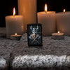 Lifestyle image of Anne Stokes Viking Skull Lighter standing on cobblestone with lit candles in the background