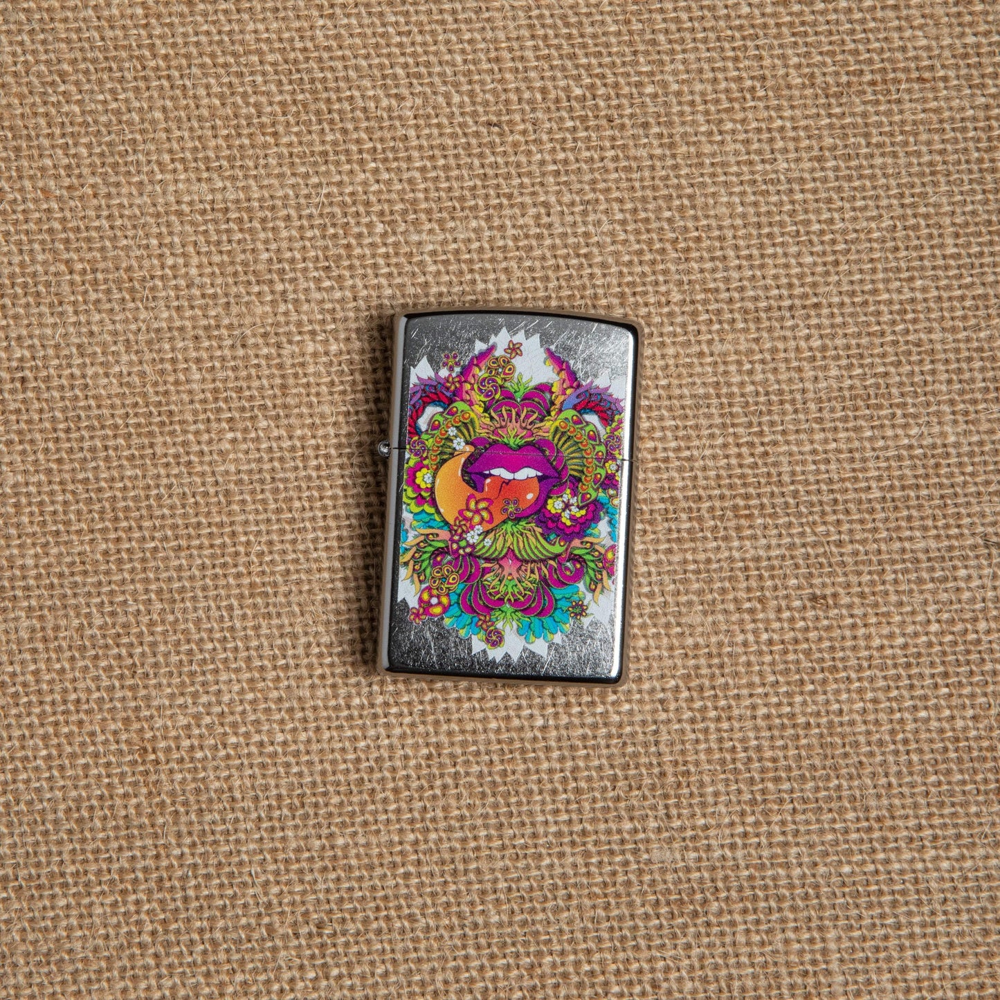 Lifestyle image of Psychedelic Lip Design Street Chrome Lighter laying on hemp fabric