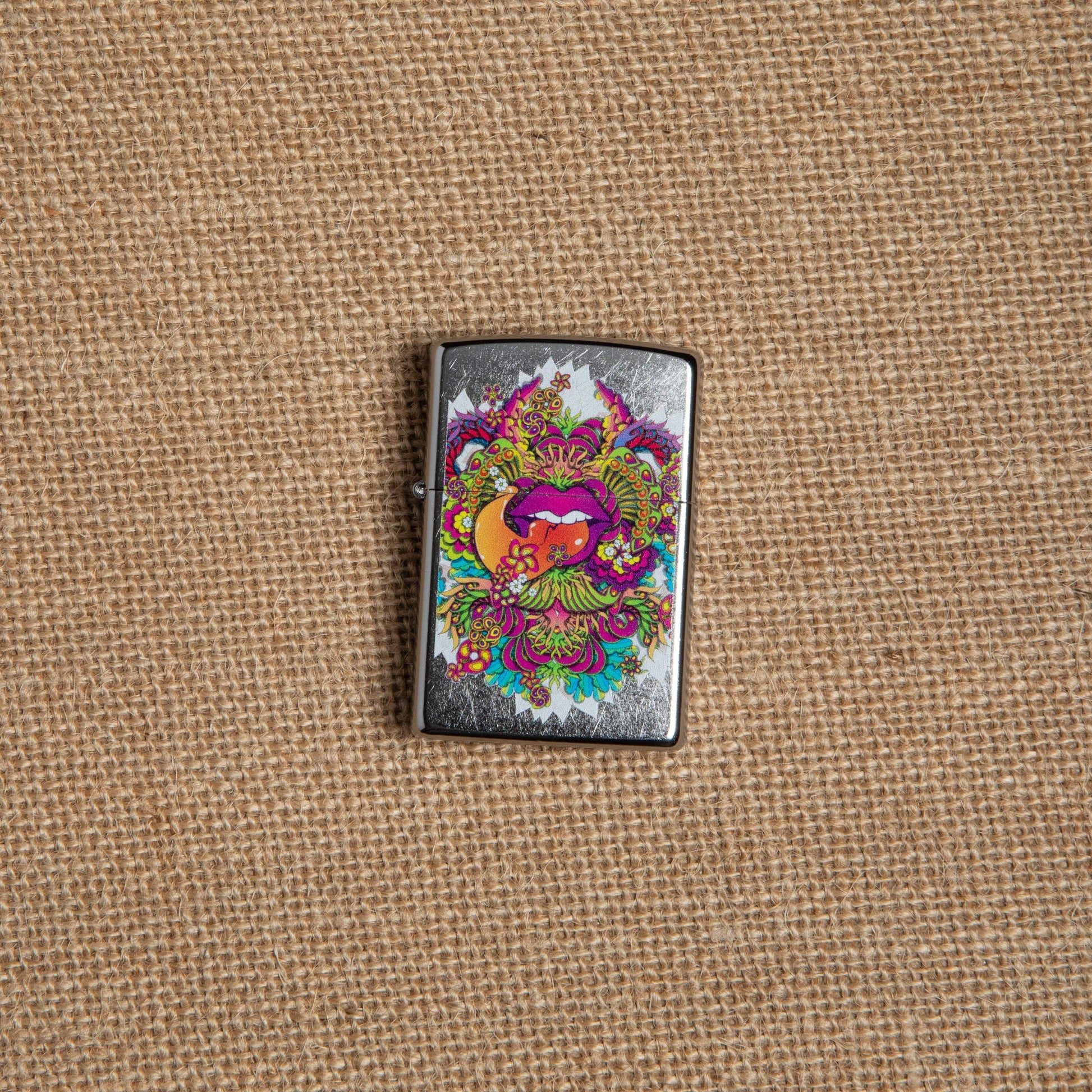 Lifestyle image of Psychedelic Lip Design Street Chrome Lighter laying on hemp fabric