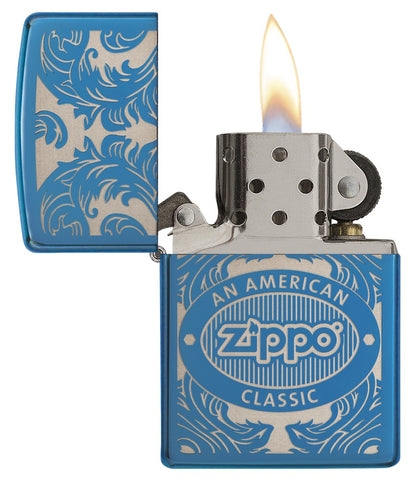 Blaues Zippo-Feuerzeug mit offener Frontansicht und Flamme, umgeben von einem lasergravierten, filigranen Motiv mit dem Zippo-Logo und 